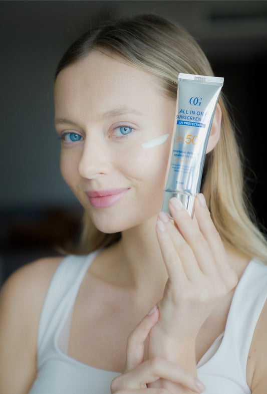 Femme tenant et appliquant le crème solaire visage SPF50+ anti-âge hydratante Ocean Glow 